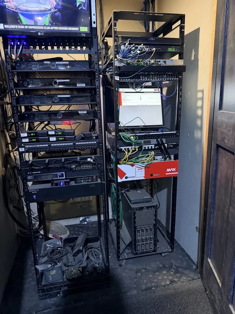 Netlink technician's completed commercial data rack — Cat6 patch panels, media players and Foxtel signal decoders labelled and cabled in a Hunter Valley hospitality venue