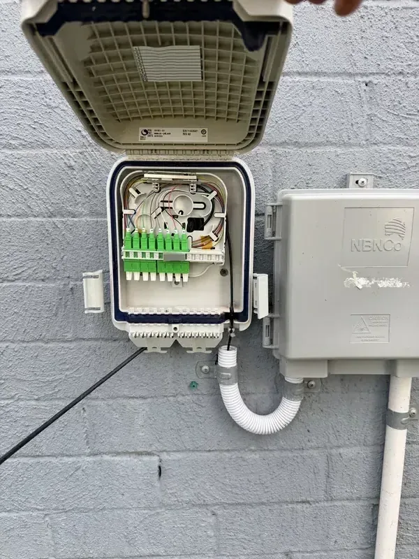 Netlink fibre-optic distribution enclosure with green SC/APC connectors mounted alongside an NBNCo NCD box on a Hunter Valley commercial premises — NBN fibre splicing and termination